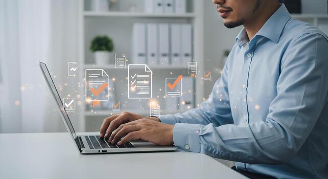Man working on laptop in modern office reviewing documents and completing tasks efficiently showcasing productivity and success in business photo
