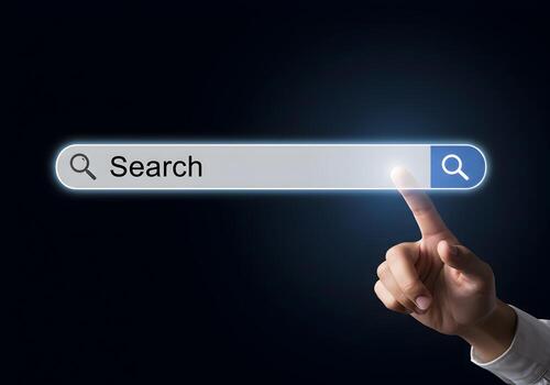 Closeup of a finger about to click on a glowing search bar on a digital screen representing the concept of internet search and exploration in a dark setting photo