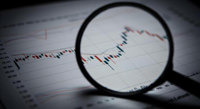 Closeup of a magnifying glass examining a detailed stock market chart displaying fluctuating data points highlighting the concept of financial analysis and market trends photo