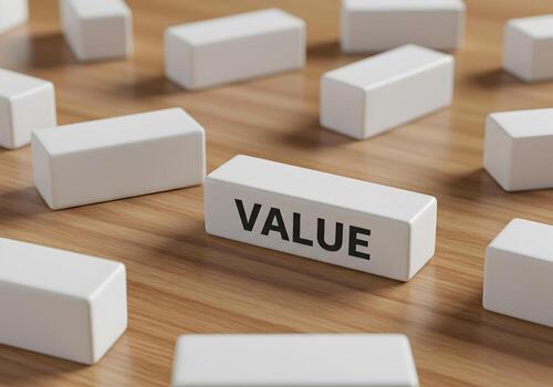 White blocks spelling out the word VALUE on a light brown wooden surface representing concepts of worth importance and financial value photo