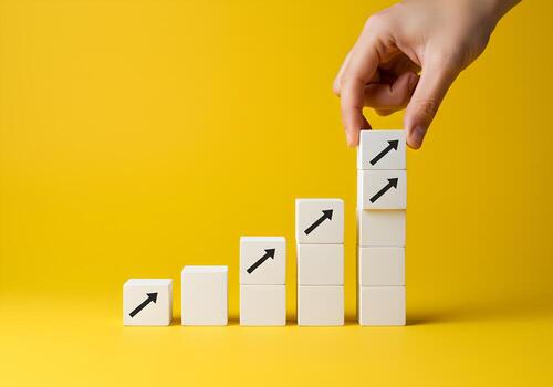 Hand arranging white blocks with upward arrows on yellow background symbolizing growth progress and achieving goals The image represents concepts of success development and strategic planning ideal fo photo