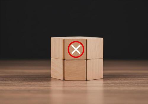 Wooden blocks with a red circled X symbol signifying rejection denial cancellation or error on a wooden table against a dark background photo