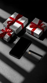 Three gifts with red ribbons a phone and a card on a surface with light and shadow patterns photo