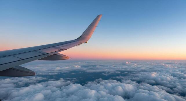 Airplane wing over fluffy clouds during a colorful sunset with a gradient sky above the horizon photo