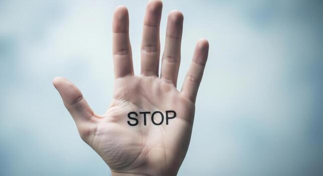 A human hand with the word stop written on the palm against a light blue gradient background photo