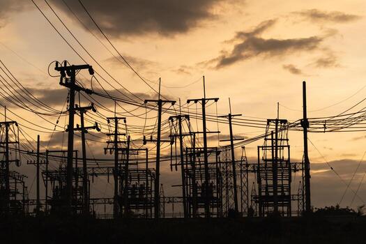 Silhouetted Power Lines and Electrical Structures Against a Dramatic Sunset Sky with Cloudy Atmosphere photo