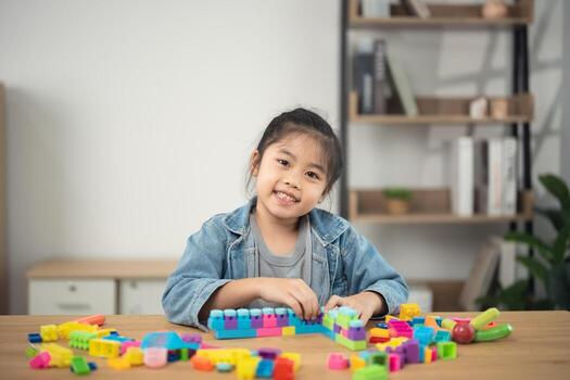 Happy child playing with colorful building blocks in bright room, engaging in creative play while developing fine motor skills and imagination photo