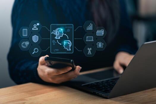 A person engages with a smartphone and a laptop, displaying AI technology and data visualization. The scene represents modern workspace innovation and digital communication. photo