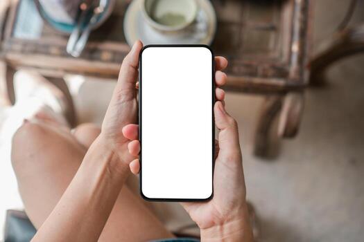 Close up of hands holding a smartphone with a blank screen in a cafe, ideal for app mockups or digital content. photo