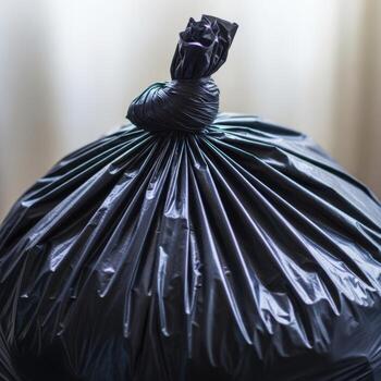 A tightly tied black garbage bag filled with contents presented isolated on a clean white background for clear visualization isolated on white background photo
