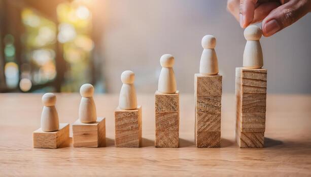 Hand placing wooden figure on ascending blocks, symbolizing growth and career advancement. photo
