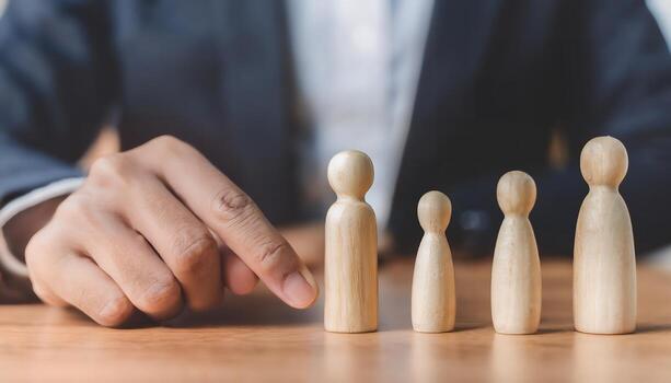 Hand pointing at wooden figure representing human resource selection. photo