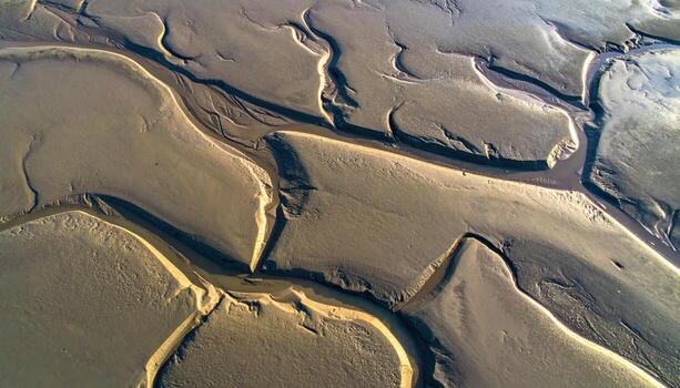 Aerial style view of tidal furrows etched in wet clay flats at low tide high angle texture with upper copy space calm coastal pattern background photo