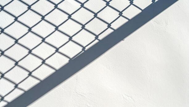 Chain link fence shadows on smooth wall graphic diagonals with right side copy space clean urban background photo
