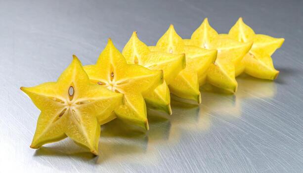 Studio still life of starfruit cross sections aligned in a diagonal track on brushed aluminum, soft reflections and clean modern composition. photo