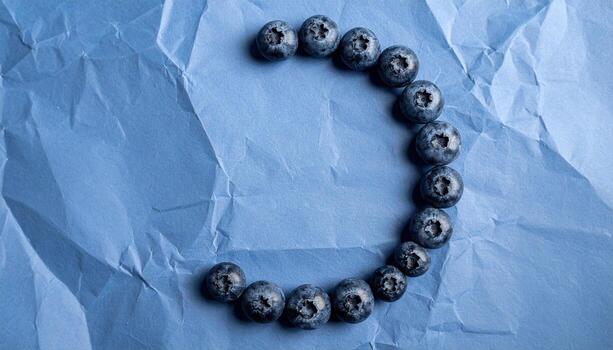 Studio still life of blueberries clustered into a crescent on slate blue paper, cool low contrast palette and serene minimal composition. photo