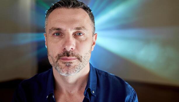 Adult with spark of inspiration eyes brighten and lips part projector dust beam behind creative studio portrait for learning innovation and brand storytelling photo