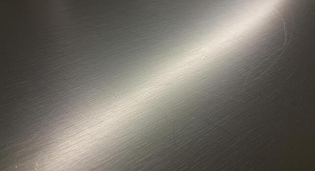 Gleaming brushed metal surface reflecting light, featu subtle scratches and a modern industrial aesthetic for backgrounds and design projects perfectly. photo