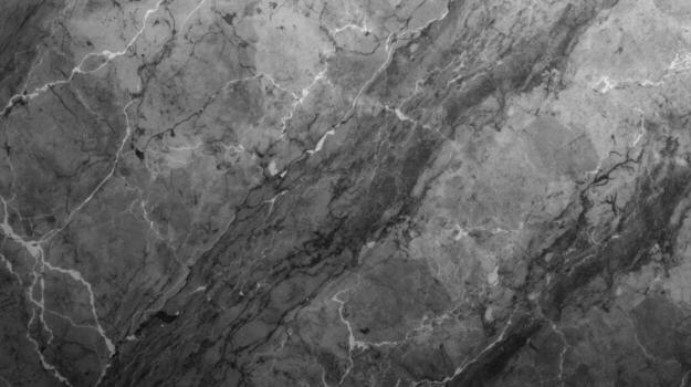 Extremely detailed black and white close up showcases the intricate and natural veining patterns found within a slab of polished marble stone surface. photo