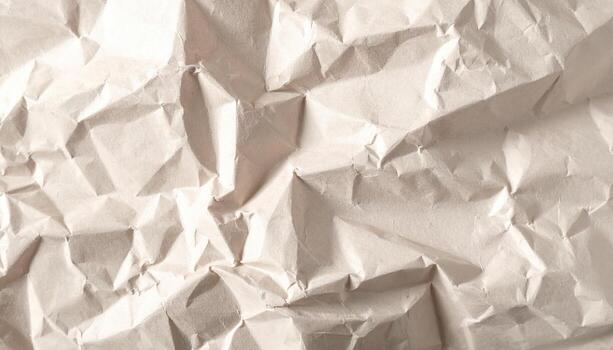 A close-up photograph reveals a highly textured surface of wrinkled beige paper, displaying a complex network of shadows and highlights across its creases. photo