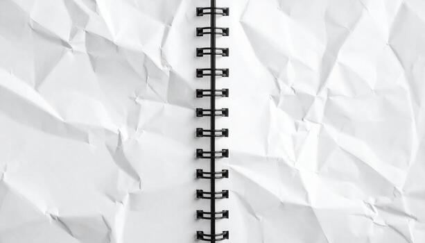 An open spiral bound notebook displays a crumpled white paper texture, creating a sense of creative chaos and potential for innovative ideas and design concepts. photo