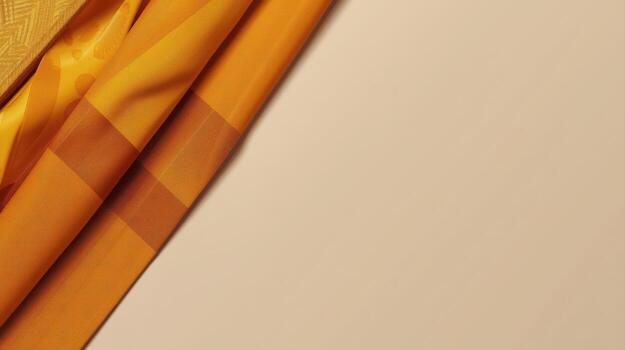 Golden fabric drapes diagonally across the frame with geometric patterns creating texture and visual interest against a plain neutral background texture effect. photo