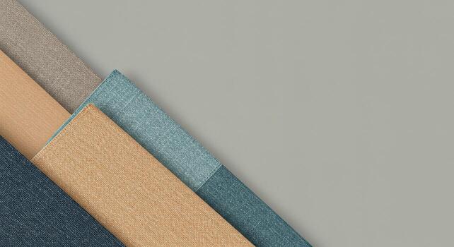 Various textured fabrics in neutral tones, including blue, beige, and gray, overlap on a solid light gray background, creating a minimalist and modern composition. photo