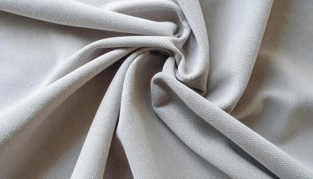 Close up shot showing a soft, smooth pale grey fabric draped with a subtle swirl, creating a gentle and elegant texture against a simple background. photo