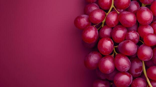 A vibrant cluster of fresh red grapes against a deep red backdrop creates a visually appealing composition. photo
