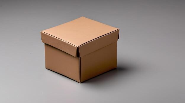 A small cardboard box with its lid partially askew sits on a gray surface, casting a soft shadow behind it. photo