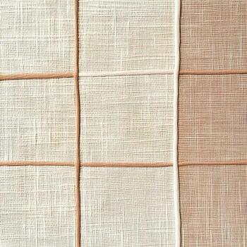Woven fabric squares in varying shades of cream and brown create a grid pattern for a textured background. photo