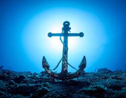 Sun shines behind old Anchor resting on Ocean floor at unknown time photo
