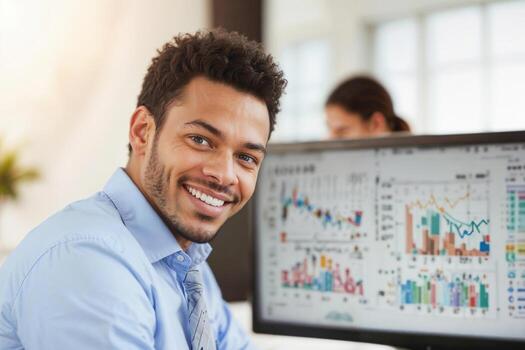 Portrait of happy financial broker is smiling in front of a computer monitor with charts in office. photo