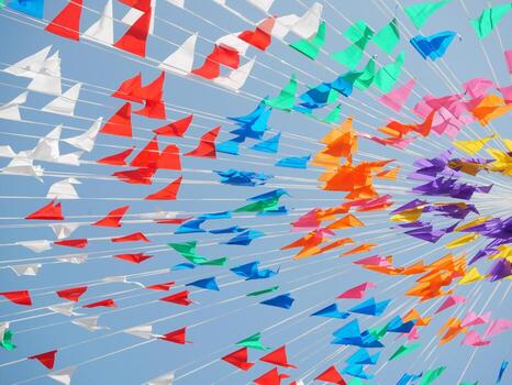 Multicolor flags and streamers create a vibrant display against a clear blue sky photo