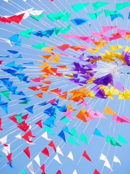 Colorful flags and streamers create a vibrant display against a clear blue sky photo