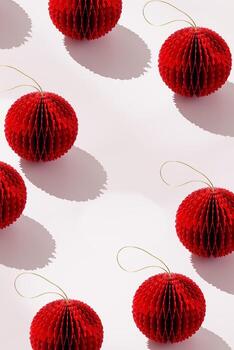 Minimal frame of red paper Christmas ornaments shaped round balls on light white, stylish holiday pattern, copyspace. Festive textured photo of paper Honeycomb baubles. Christmas, New Year concept.