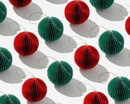 Top view of honeycomb paper Christmas ornaments in minimal trend pattern on light gray background. Red and green New Year balls with sun shadows creating vivid linear layout modern holiday themes. photo