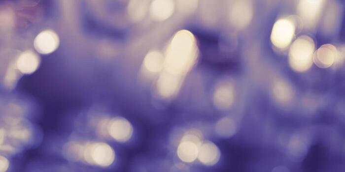 Yellow lights bokeh on blue violet background. Bright defocused image with round bokeh very peri trend colored. Christmas holiday blurred banner. Abstract composition with light, bokeh, glitter photo