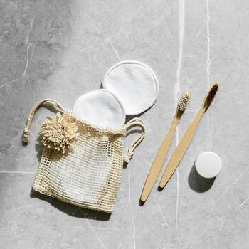 Hygiene product as bamboo toothbrushes, toothpaste, reusable pads on grey marble background with natural light, eco-friendly items for self care, zero waste concept. Minimal pattern, neutral tone photo