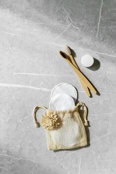 Hygiene products as bamboo toothbrushes, toothpaste, reusable pads on grey marble background with natural light, eco-friendly items for self care, zero waste concept. Minimal pattern, neutral tone photo