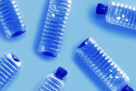 Pattern from Clear plastic water bottles with blue cap on light blue background with soft shadow, Minimal top view, themes of ecology, recycling, sustainable living, reduce disposable plastic photo