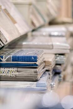 Neatly stacked bedding sets in various colors and patterns displayed on shelves, showcasing textile textures and organized presentation in a retail environment photo