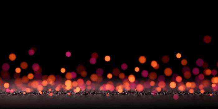 Numerous vibrant orange red and pink bokeh lights float over a dark textured surface creating a festive abstract background photo