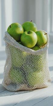 Eco friendly reusable produce bag with fresh green apples on light background photo