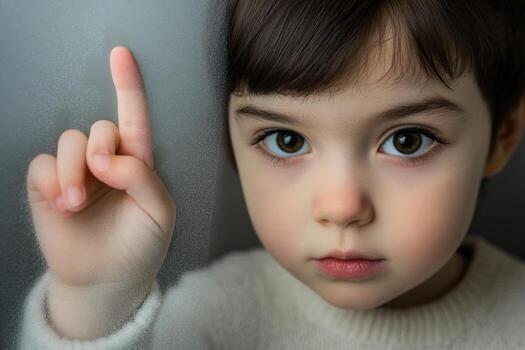 Thoughtful child with expressive eyes and finger raised, immersed in quiet contemplation indoors photo