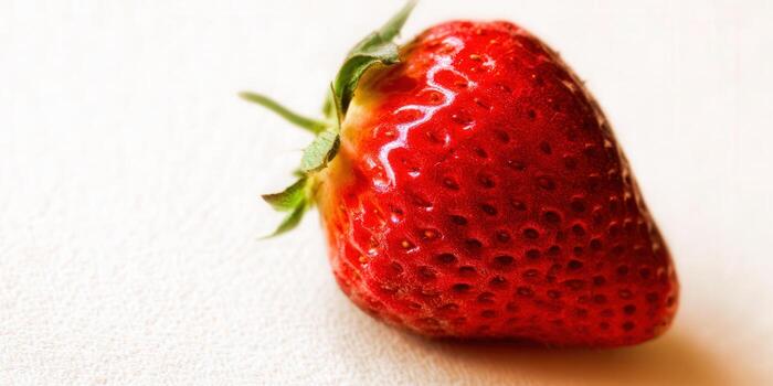 A single, ripe strawberry, perfectly showcasing its vibrant red color and texture. photo