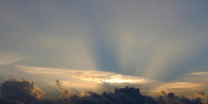 The sun shines through dramatic clouds, creating a beautiful sunset scene. photo