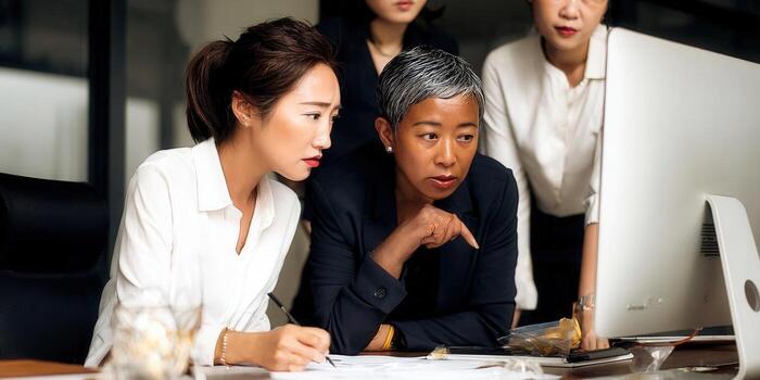 Businesswomen huddled around a computer, reviewing data and strategizing together. photo