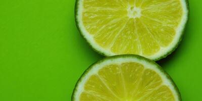 Fresco Lima rebanadas en contra un vívido verde fondo, destacando el de frutas textura. foto