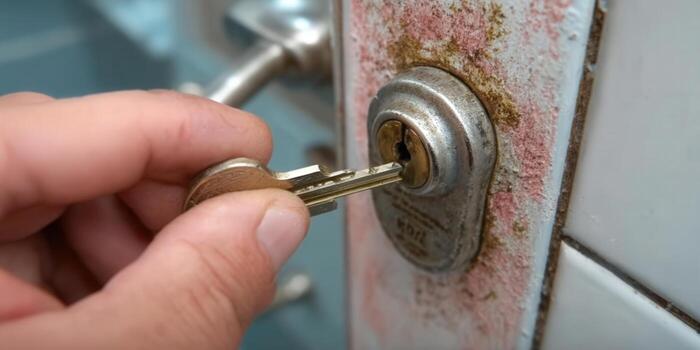 A person is inserting a key into the lock, ready to open the door and enter. photo